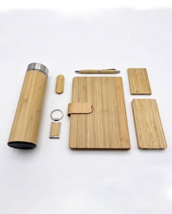 Bamboo desk set laid out: insulated bottle, wooden pen, notebook with strap, two small bamboo boards, a bamboo card/phone case, and keychain.