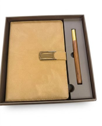 Tan leather notebook/planner with a strap buckle, placed in a gift box beside a wooden pen with brass cap out of the tray in a brown gift box set.
