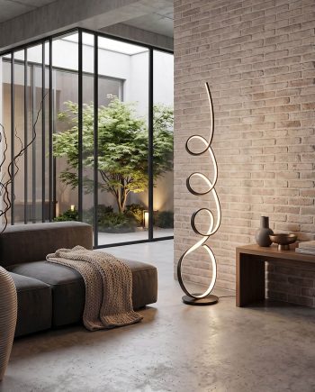 Modern living area with a sculptural spiral floor lamp, brick wall, and glass wall opening to an indoor garden.