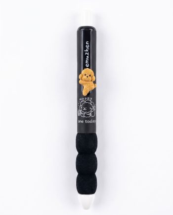 Black pen with a small orange dog charm clipped to its body and a white graphic that says 'Happy one today' on the lower half.