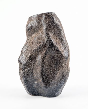 Abstract sculpture with a rugged, pebbled surface in dark brown and black against a white backdrop.
